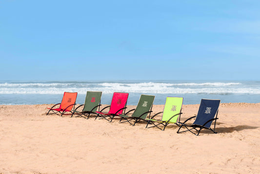 Sillas de playa plegables premium KTK Kontiki en diferentes colores alineadas en la arena frente al mar, diseño portátil, ligero y cómodo, ideales para verano, vacaciones y camping en España y Portugal.
