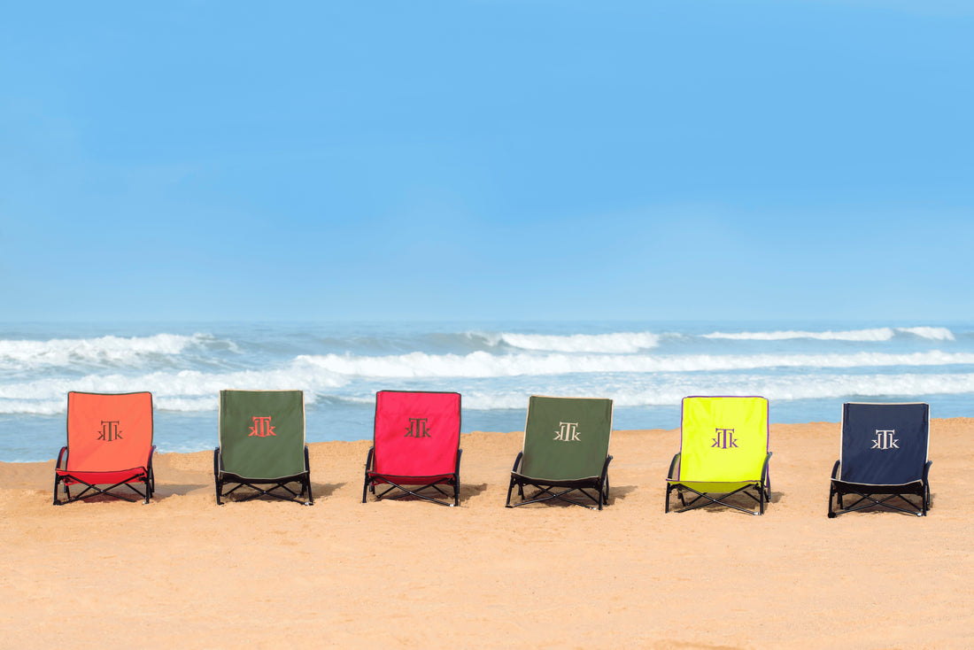 Sillas de playa plegables KTK Kontiki en varios colores sobre la arena frente al mar, diseño portátil, ergonómico y ultraligero ideal para playa, camping o jardín.